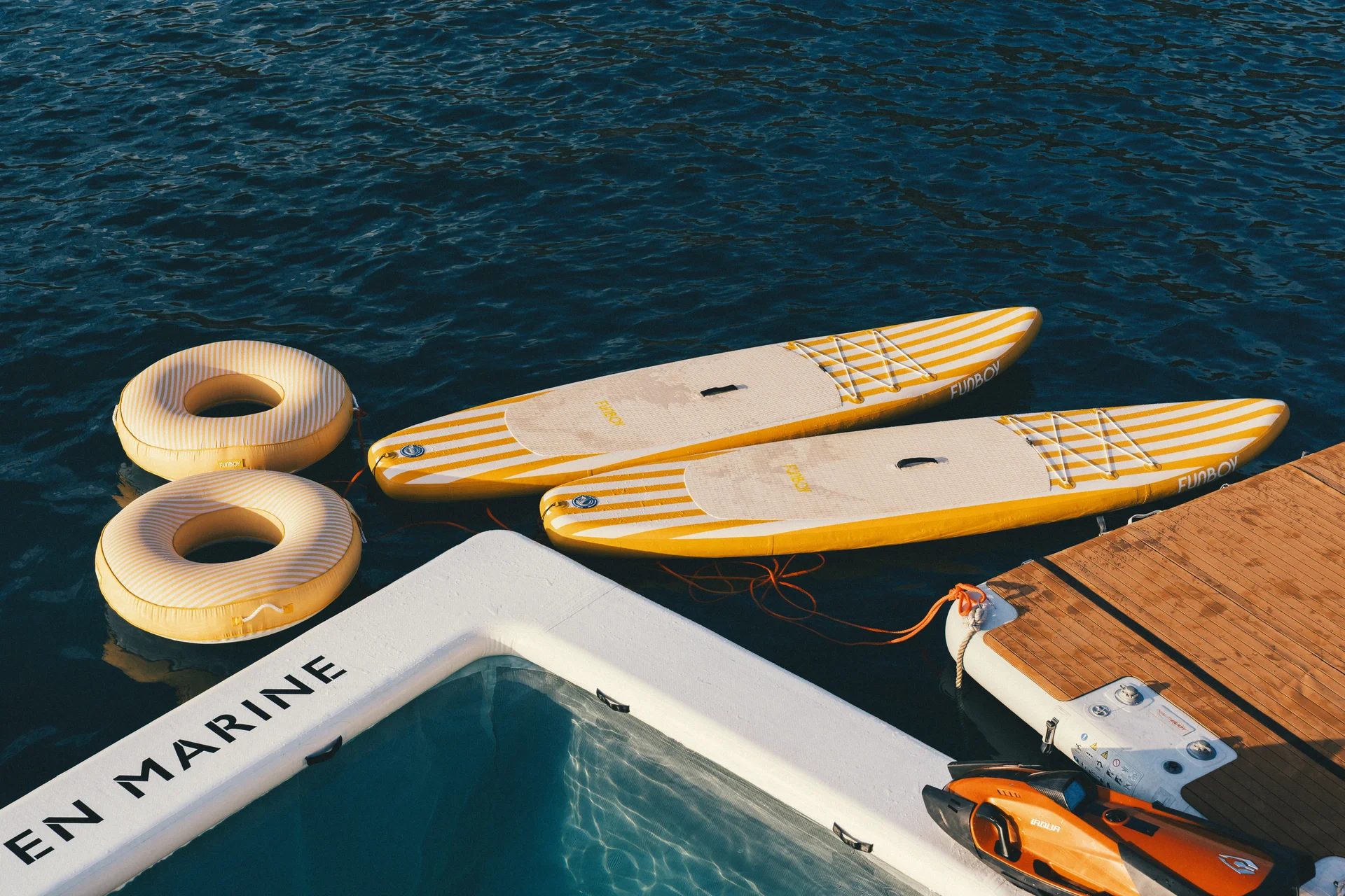 Yellow paddleboards and floats beside SCALLOBS on the Andaman Sea