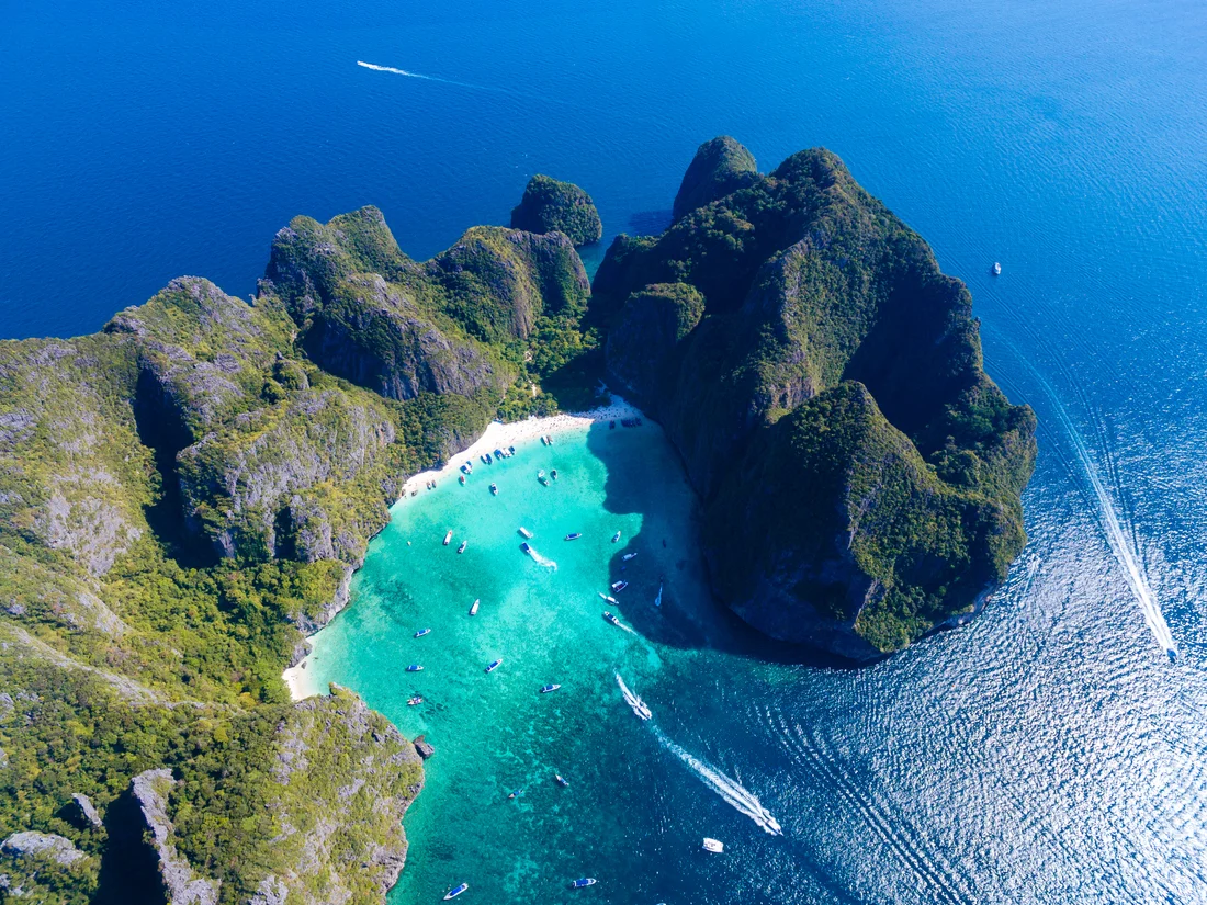 An aerial view of a turquoise bay surrounded by the limestone cliffs of the Phi Phi Islands